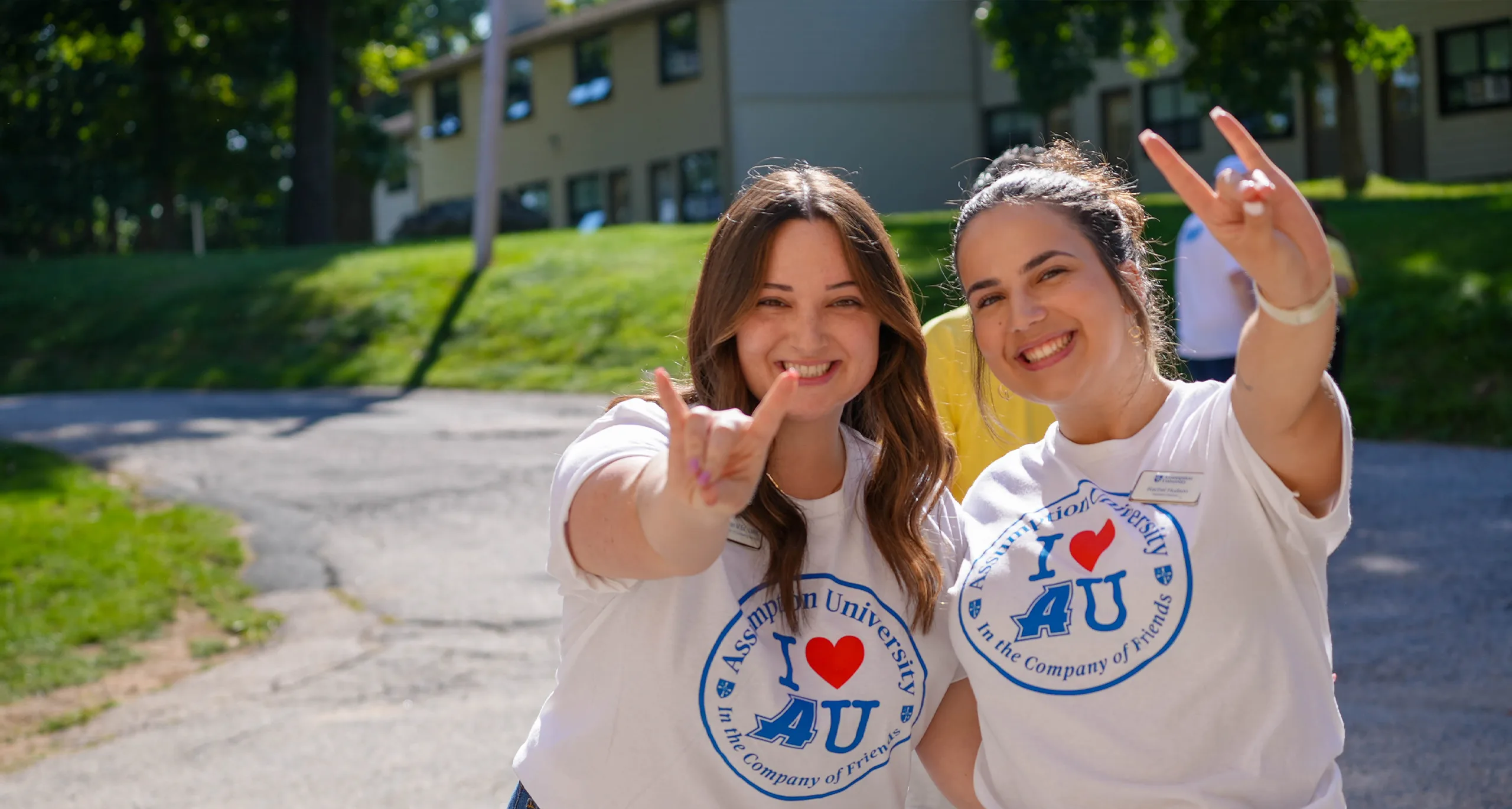 Two Assumption students wearing white t-shirts and holding up a 